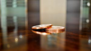 image of two coins, one half on top of the other, sitting on a wood table top
